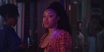 Movie still from “Heist 88” (2023), directed by Menhaj Huda – A woman in a red jacket standing in a room; Close Up shot, Over the shoulder angle