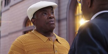 Movie still from “Heist 88” (2023), directed by Menhaj Huda – An older black man wearing a white hat; Close Up shot, Over the shoulder angle