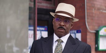 Movie still from “Heist 88” (2023), directed by Menhaj Huda – An older man wearing a hat and a suit; Close Up shot, Low angle