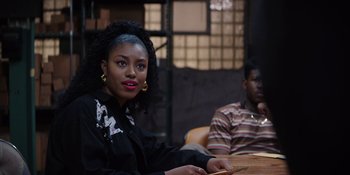 Movie still from “Heist 88” (2023), directed by Menhaj Huda – A woman sitting next to a man at a table; Close Up shot, Over the shoulder angle