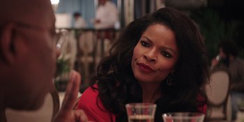 Movie still from “Heist 88” (2023), directed by Menhaj Huda – A woman sitting at a table with a glass of wine; Close Up shot, Over the shoulder angle