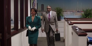 Movie still from “Heist 88” (2023), directed by Menhaj Huda – A man and a woman walking down a hall way; Wide shot, Low angle