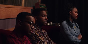 Movie still from “Heist 88” (2023), directed by Menhaj Huda – Two young men sitting in front of a sound board; Medium shot, Over the shoulder angle