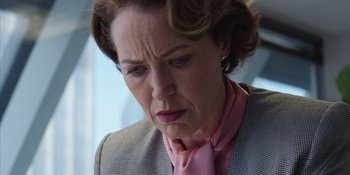 Movie still from “Heist 88” (2023), directed by Menhaj Huda – An older woman wearing a pink neck tie; Close Up shot, Low angle