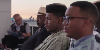 Movie still from “Heist 88” (2023), directed by Menhaj Huda – A group of men sitting next to each other on a bench; Close Up shot, Over the shoulder angle