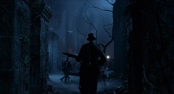 Movie still from “Hellboy” (2004), directed by Guillermo del Toro – A man holding a gun while standing in the dark; Wide shot, Low angle