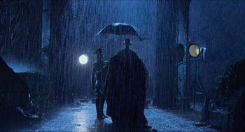 Movie still from “Hellboy” (2004), directed by Guillermo del Toro – Two people under an umbrella in the rain at night; Wide shot, Low angle