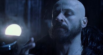 Movie still from “Hellboy” (2004), directed by Guillermo del Toro – A man with a long beard is smoking a cigarette; Close Up shot, Over the shoulder angle