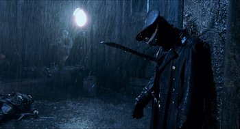 Movie still from “Hellboy” (2004), directed by Guillermo del Toro – A person in a black outfit holding a sword in the rain; Medium shot, Low angle