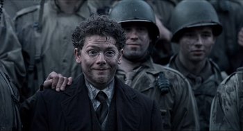 Movie still from “Hellboy” (2004), directed by Guillermo del Toro – A man in a suit and tie standing in front of soldiers; Close Up shot, Over the shoulder angle