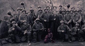 Movie still from “Hellboy” (2004), directed by Guillermo del Toro – A group of men in military uniforms posing for a picture; Wide shot, High angle