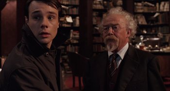 Movie still from “Hellboy” (2004), directed by Guillermo del Toro – A man and a young boy standing next to each other in a library; Close Up shot, Over the shoulder angle