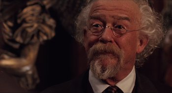 Movie still from “Hellboy” (2004), directed by Guillermo del Toro – An older man with a beard and glasses; Close Up shot, Over the shoulder angle