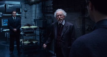 Movie still from “Hellboy” (2004), directed by Guillermo del Toro – An older man in a suit and tie in a kitchen; Medium shot, Over the shoulder angle