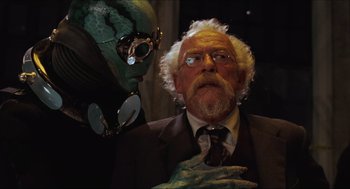 Movie still from “Hellboy” (2004), directed by Guillermo del Toro – An old man in a suit and tie next to an alien; Close Up shot, Over the shoulder angle