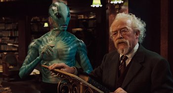 Movie still from “Hellboy” (2004), directed by Guillermo del Toro – An old man with a guitar and a man with an alien costume; Medium shot, Over the shoulder angle