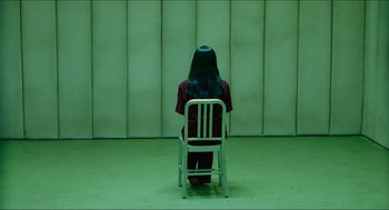 Movie still from “Hellboy” (2004), directed by Guillermo del Toro – A person sitting in a chair in a room; Wide shot, Over the shoulder angle