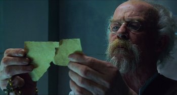 Movie still from “Hellboy” (2004), directed by Guillermo del Toro – An old man holding a piece of paper in front of a mirror; Close Up shot, Low angle