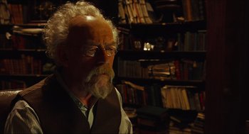 Movie still from “Hellboy” (2004), directed by Guillermo del Toro – An old man with a beard and glasses in a room full of books; Close Up shot, Low angle