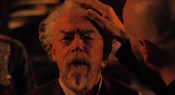 Movie still from “Hellboy” (2004), directed by Guillermo del Toro – An old man with a beard and glasses getting his hair combed; Close Up shot, Over the shoulder angle