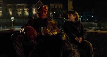 Movie still from “Hellboy” (2004), directed by Guillermo del Toro – A man and a boy sitting next to each other; Medium shot, Over the shoulder angle