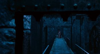 Movie still from “Hellboy” (2004), directed by Guillermo del Toro – A person sitting on a bridge in a dark place; Extreme Wide shot, High angle