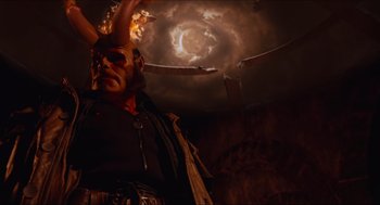 Movie still from “Hellboy” (2004), directed by Guillermo del Toro – A demonic looking figure in front of an exploding sky; Medium shot, Low angle