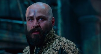 Movie still from “Hellboy” (2004), directed by Guillermo del Toro – A bald man with a beard and a blue jacket; Close Up shot, Low angle