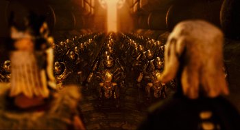 Movie still from “Hellboy II: The Golden Army” (2008), directed by Guillermo del Toro – A group of soldiers sitting in rows in front of a wall; Wide shot, High angle