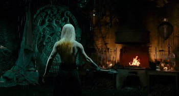 Movie still from “Hellboy II: The Golden Army” (2008), directed by Guillermo del Toro – A man with long white hair standing in front of an open fire; Medium shot, Over the shoulder angle