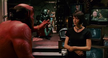 Movie still from “Hellboy II: The Golden Army” (2008), directed by Guillermo del Toro – A woman in a black shirt is talking to a man in a red suit; Medium shot, Over the shoulder angle