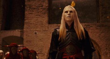 Movie still from “Hellboy II: The Golden Army” (2008), directed by Guillermo del Toro – A man with long blonde hair wearing a red and black outfit; Medium shot, Low angle
