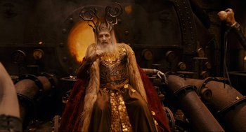 Movie still from “Hellboy II: The Golden Army” (2008), directed by Guillermo del Toro – An old man dressed in a costume sitting in a chair; Medium shot, Low angle