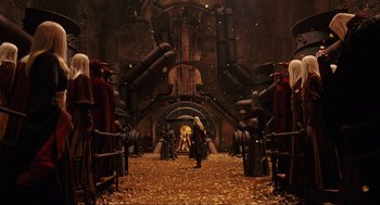 Movie still from “Hellboy II: The Golden Army” (2008), directed by Guillermo del Toro – A group of people standing in a room with lots of gold; Extreme Wide shot, High angle