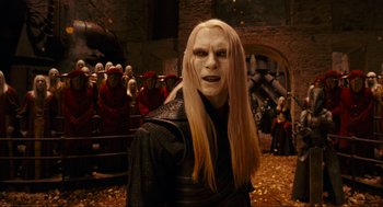 Movie still from “Hellboy II: The Golden Army” (2008), directed by Guillermo del Toro – A man with long blonde hair wearing a black outfit; Medium shot, Over the shoulder angle