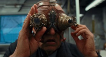 Movie still from “Hellboy II: The Golden Army” (2008), directed by Guillermo del Toro – An older man wearing goggles looking through a pair of binoculars; Close Up shot, Over the shoulder angle