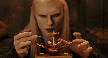 Movie still from “Hellboy II: The Golden Army” (2008), directed by Guillermo del Toro – A man with long blonde hair is holding a candle holder; Close Up shot, High angle