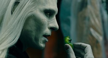 Movie still from “Hellboy II: The Golden Army” (2008), directed by Guillermo del Toro – A man with a white face holding a green object; Extreme Close Up shot, Overhead angle