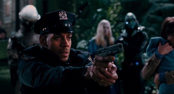 Movie still from “Hellboy II: The Golden Army” (2008), directed by Guillermo del Toro – A police officer holding a gun in front of two other people; Close Up shot, Over the shoulder angle