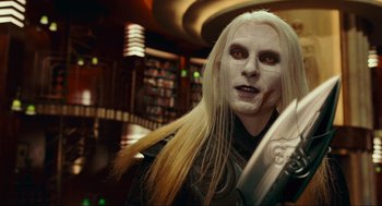 Movie still from “Hellboy II: The Golden Army” (2008), directed by Guillermo del Toro – A man with long white hair holding a sword in a library; Close Up shot, Over the shoulder angle