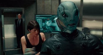 Movie still from “Hellboy II: The Golden Army” (2008), directed by Guillermo del Toro – A woman standing next to a man wearing a mask in front of a computer screen; Close Up shot, Over the shoulder angle