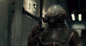 Movie still from “Hellboy II: The Golden Army” (2008), directed by Guillermo del Toro – A man in a suit and helmet is pointing to the side; Medium shot, High angle