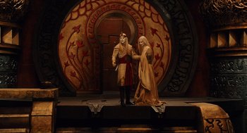 Movie still from “Hellboy II: The Golden Army” (2008), directed by Guillermo del Toro – A man and a woman standing on a stage in front of an archway; Wide shot, High angle