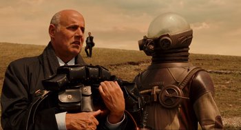 Movie still from “Hellboy II: The Golden Army” (2008), directed by Guillermo del Toro – A man in a suit and tie standing next to a man in a suit; Medium shot, Over the shoulder angle