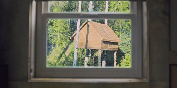 Movie still from “Hereditary” (2018), directed by Ari Aster – A view of a tree house through a window; Extreme Wide shot, Low angle