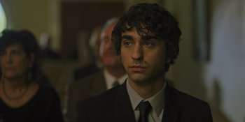 Movie still from “Hereditary” (2018), directed by Ari Aster – A man in a suit and tie standing next to another man in a suit and tie; Close Up shot, Over the shoulder angle