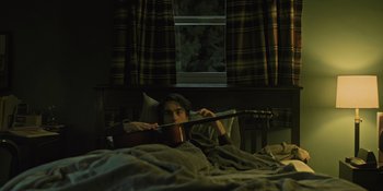 Movie still from “Hereditary” (2018), directed by Ari Aster – A man laying in a bed with a guitar in front of him; Medium shot, High angle