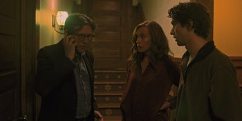 Movie still from “Hereditary” (2018), directed by Ari Aster – A group of people standing next to each other in a room; Medium shot, Over the shoulder angle