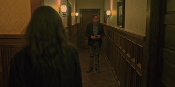 Movie still from “Hereditary” (2018), directed by Ari Aster – A man standing in the hallway of a building; Wide shot, Over the shoulder angle