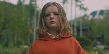 Movie still from “Hereditary” (2018), directed by Ari Aster – A young girl wearing a red hooded sweatshirt; Medium shot, Low angle